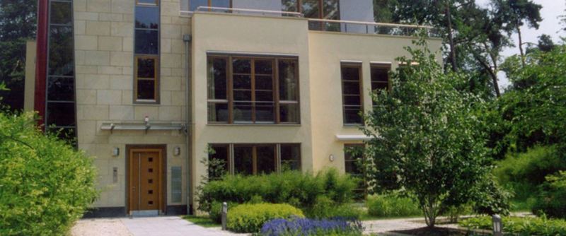 Villa im Grünen mit raumhohen Fensterelementen und einer Haustür aus Eiche.